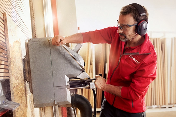 Person arbeitet mit einer Tischkreissäge an Holz.